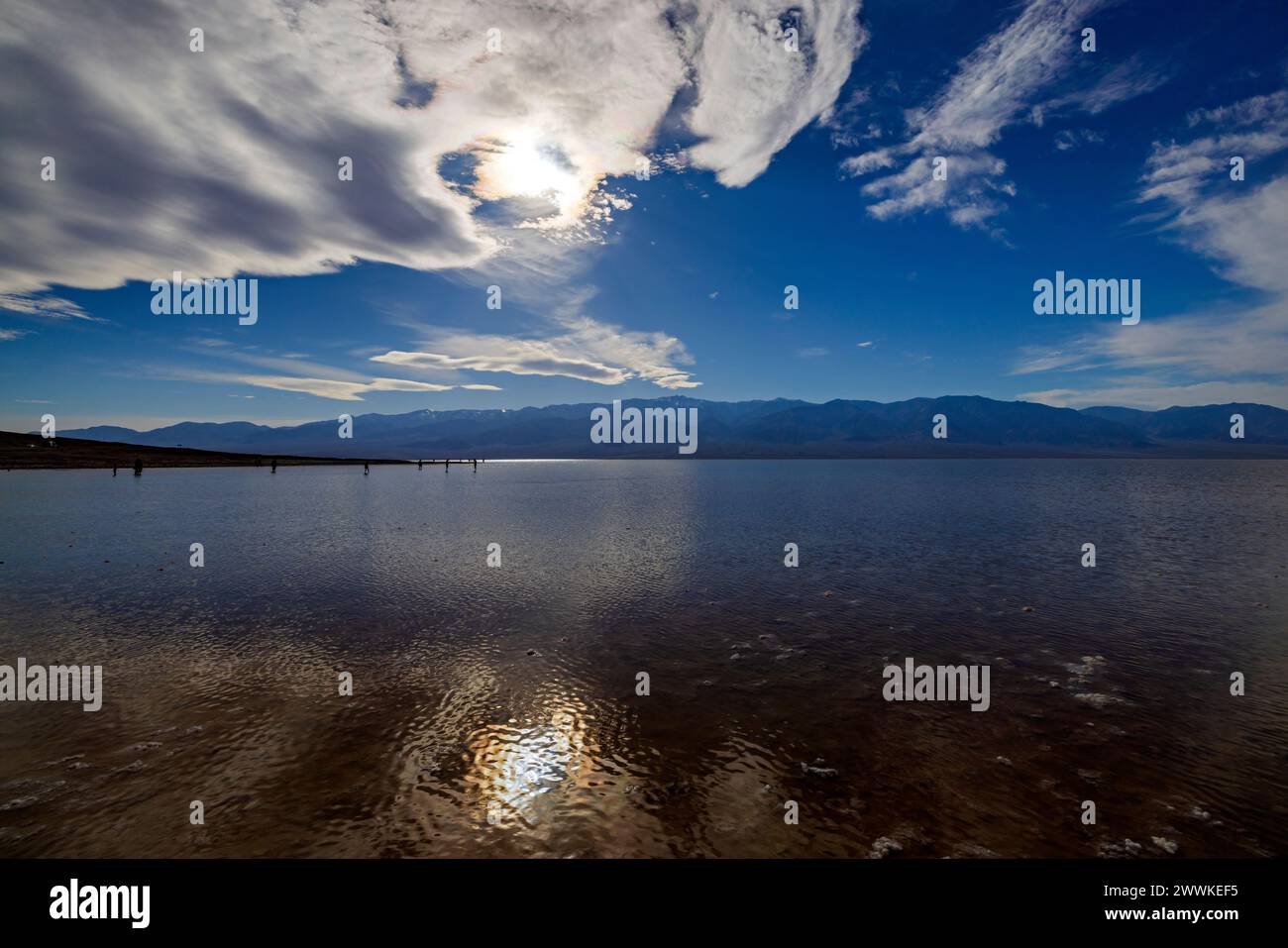 Menschen in der Ferne waten im kürzlich entstandenen Lake Manly im Badwater Basin des Death Valley National Park, Inyo County, Kalifornien, USA. Stockfoto