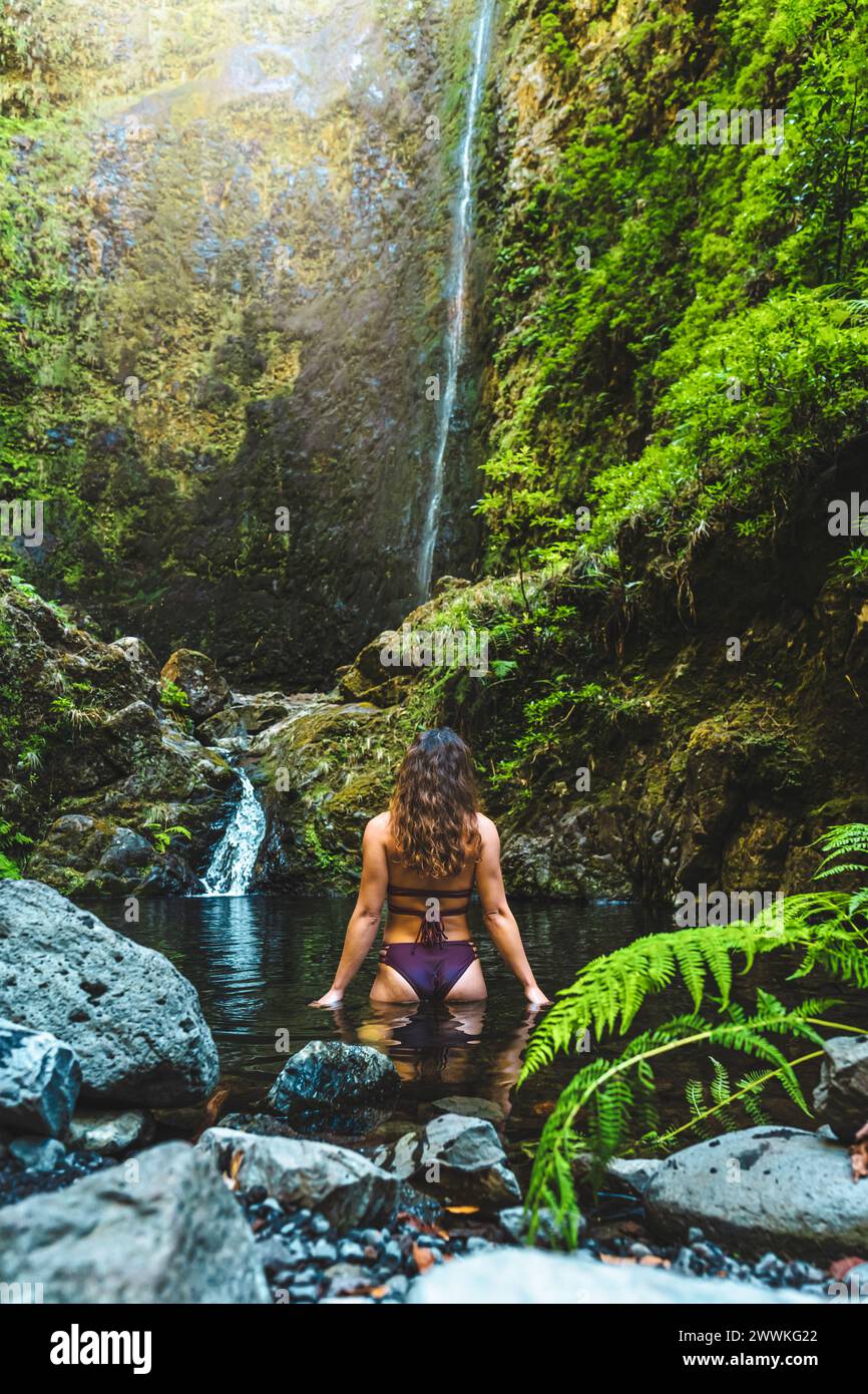Beschreibung: Touristenfrau im Bikini genießt ein erfrischendes Bad im Pool an einem malerischen überwucherten Wasserfall im Madeira Regenwald. Levada von Caldei Stockfoto