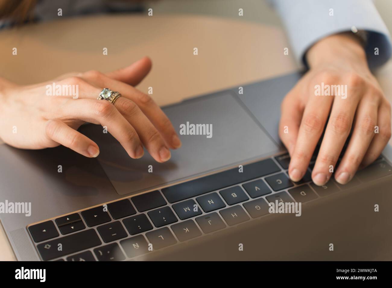 Hände einer Frau, die formell in einem hellblauen Hemd gekleidet ist und auf ihrem Laptop schreibt Stockfoto