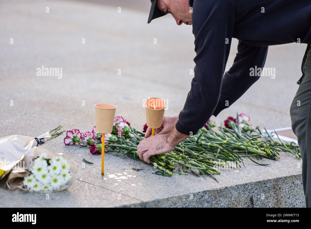 Melbourne, Australien. März 2024. Ein Mann legt Blumen und platziert Trauerkerzen an einer provisorischen Gedenkstätte in der Nähe der ewigen Flamme am Shrine of Remembrance in Melbourne, Australien, zum Gedenken an die Opfer von Terroristen im Crocus City Hall in Russland. (Foto: Alexander Bogatyrev/SOPA Images/SIPA USA) Credit: SIPA USA/Alamy Live News Stockfoto