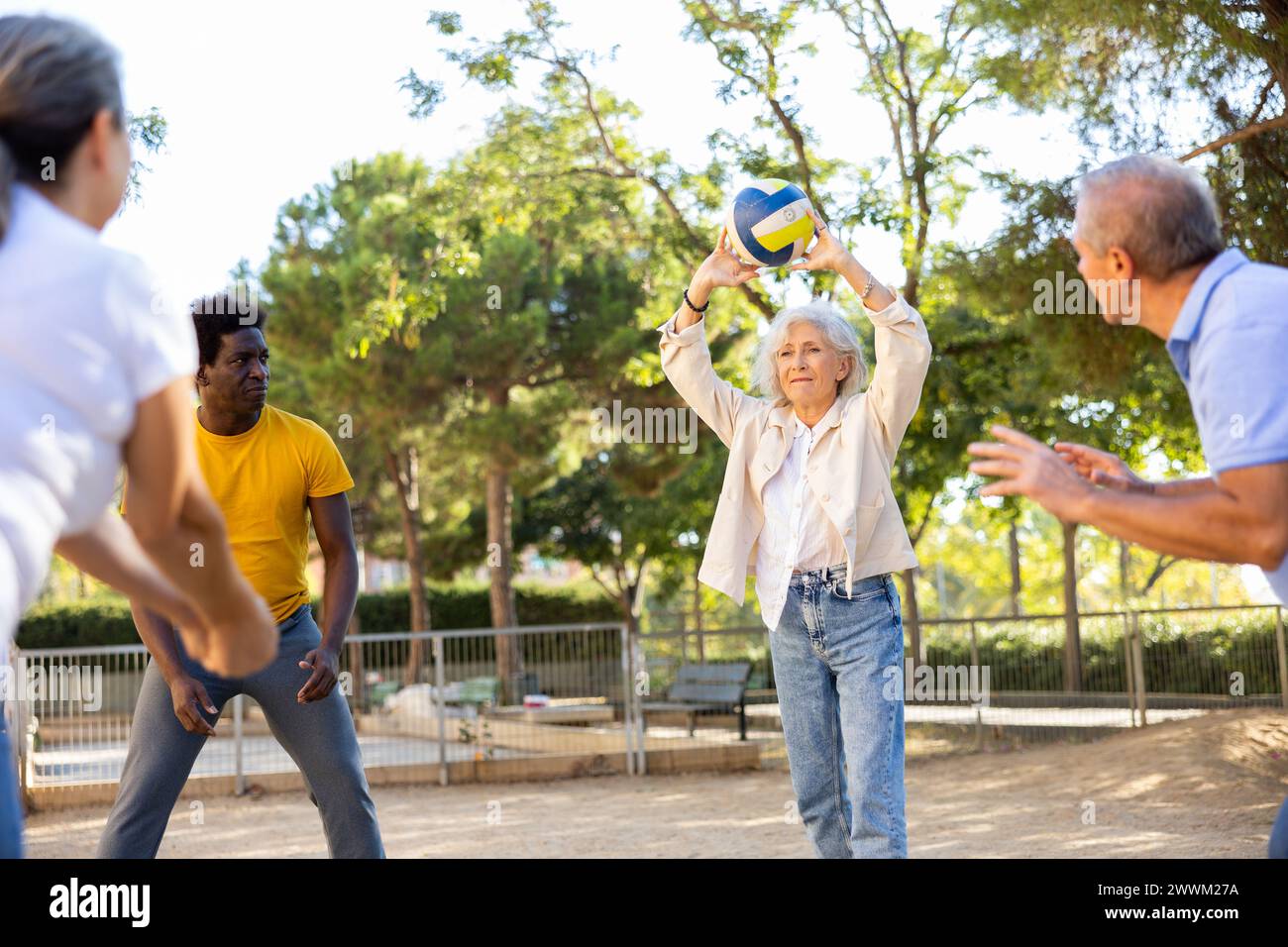 Alte multinationale Menschen spielen Volleyball-Aktivität auf einem Sommerspielplatz für Sport im Frühling draußen Stockfoto
