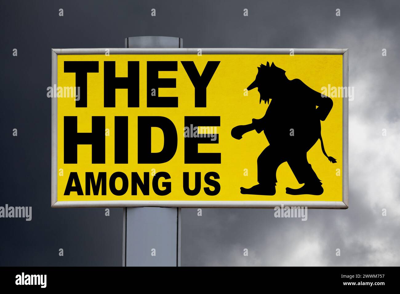 Nahaufnahme auf einer gelben Plakatwand vor einem bewölkten Himmel mit der Aufschrift „Sie verstecken sich unter uns“ in der Mitte neben einem Troll. Stockfoto