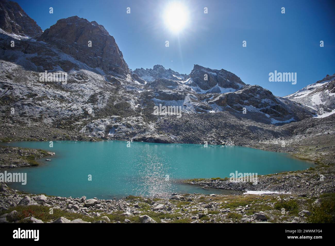 Unberührter Mountain Lake mit schneebedeckten Gipfeln unter einem klaren blauen Himmel am Mittag Stockfoto