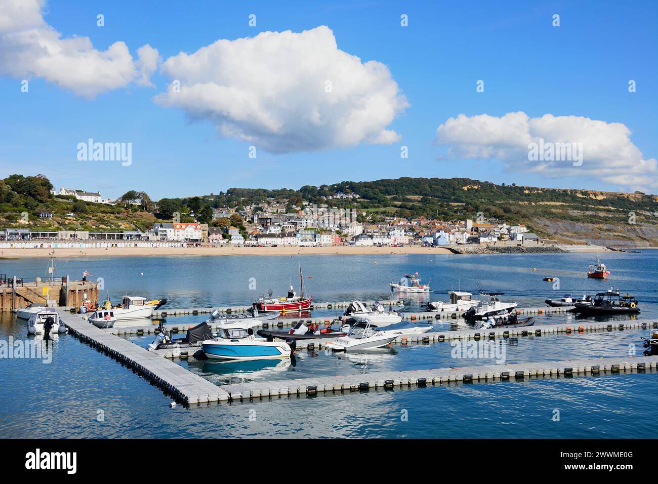 Die Boote liegen entlang des schwimmenden Pontons mit Blick auf die Stadt und die Jurassic Coast, Lyme Regis, Dorset, Großbritannien, Europa. Stockfoto