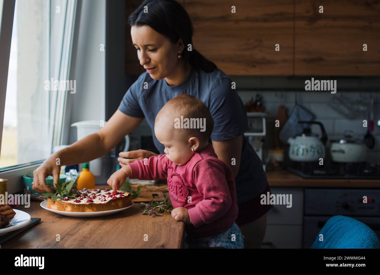 Ein kleines Kind nimmt Beeren aus einer Geburtstagskuche Stockfoto
