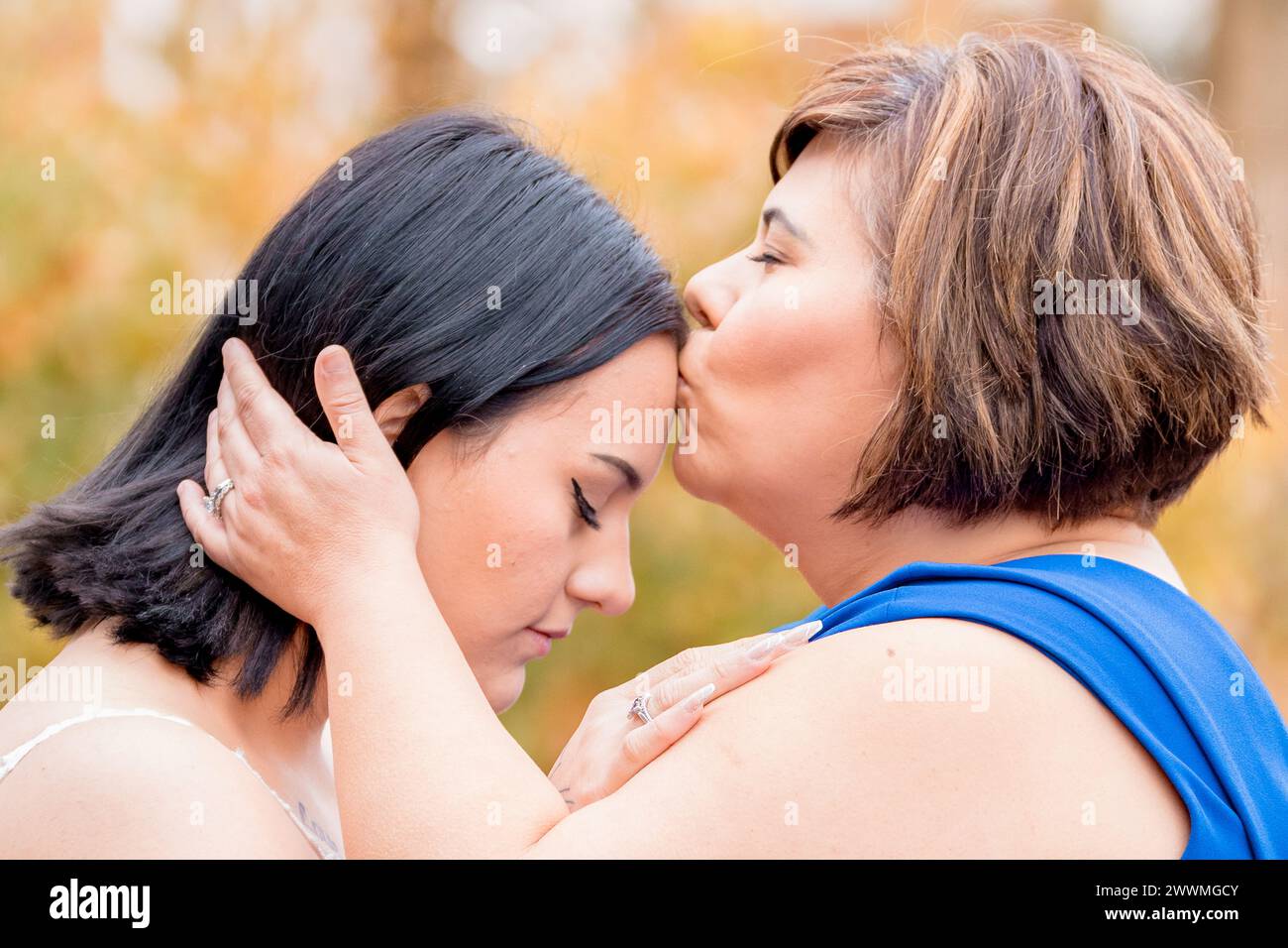 Eine Mutter, die ihre Tochter auf die Stirn küsst Stockfoto