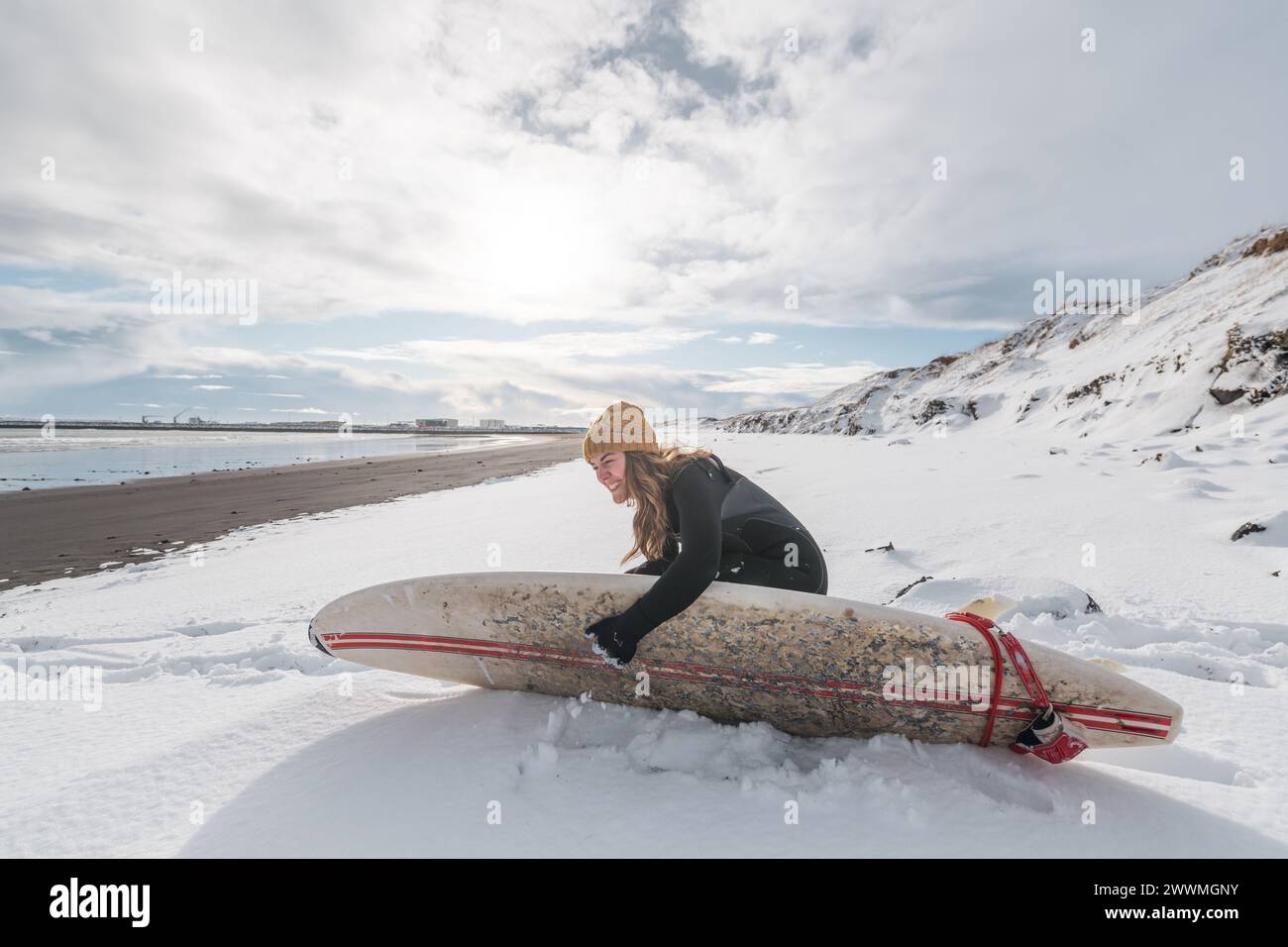 Frau, die am Strand mit Surfbrett steht, Winter island Stockfoto
