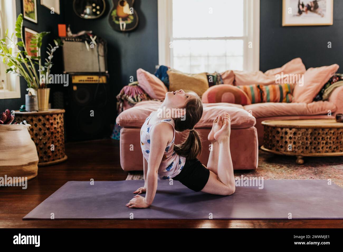 Das junge Mädchen macht tagsüber Yoga in ihrem Wohnzimmer Stockfoto
