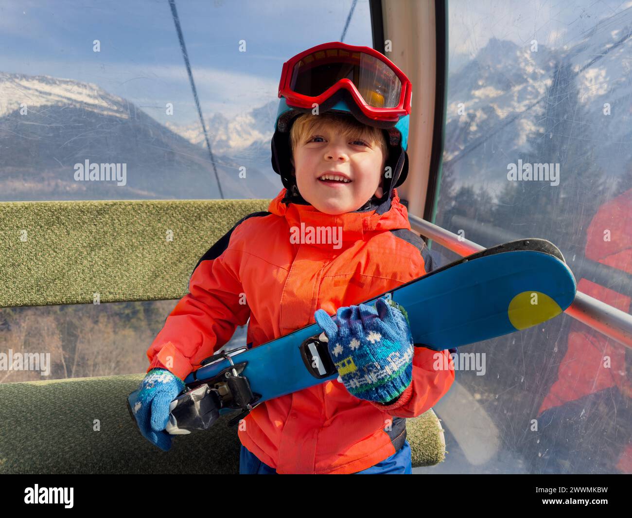 Happy Boy Hold Skier genießen eine schneebedeckte Seilbahnfahrt in den Alpen Stockfoto