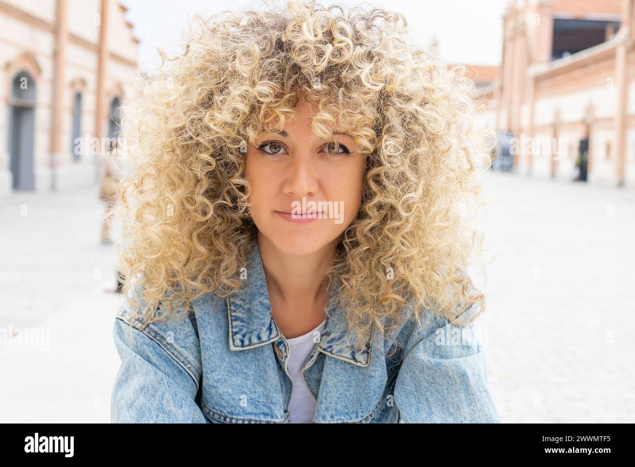 Porträt einer lächelnden jungen kaukasierin mit lockigen blonden Haaren Stockfoto