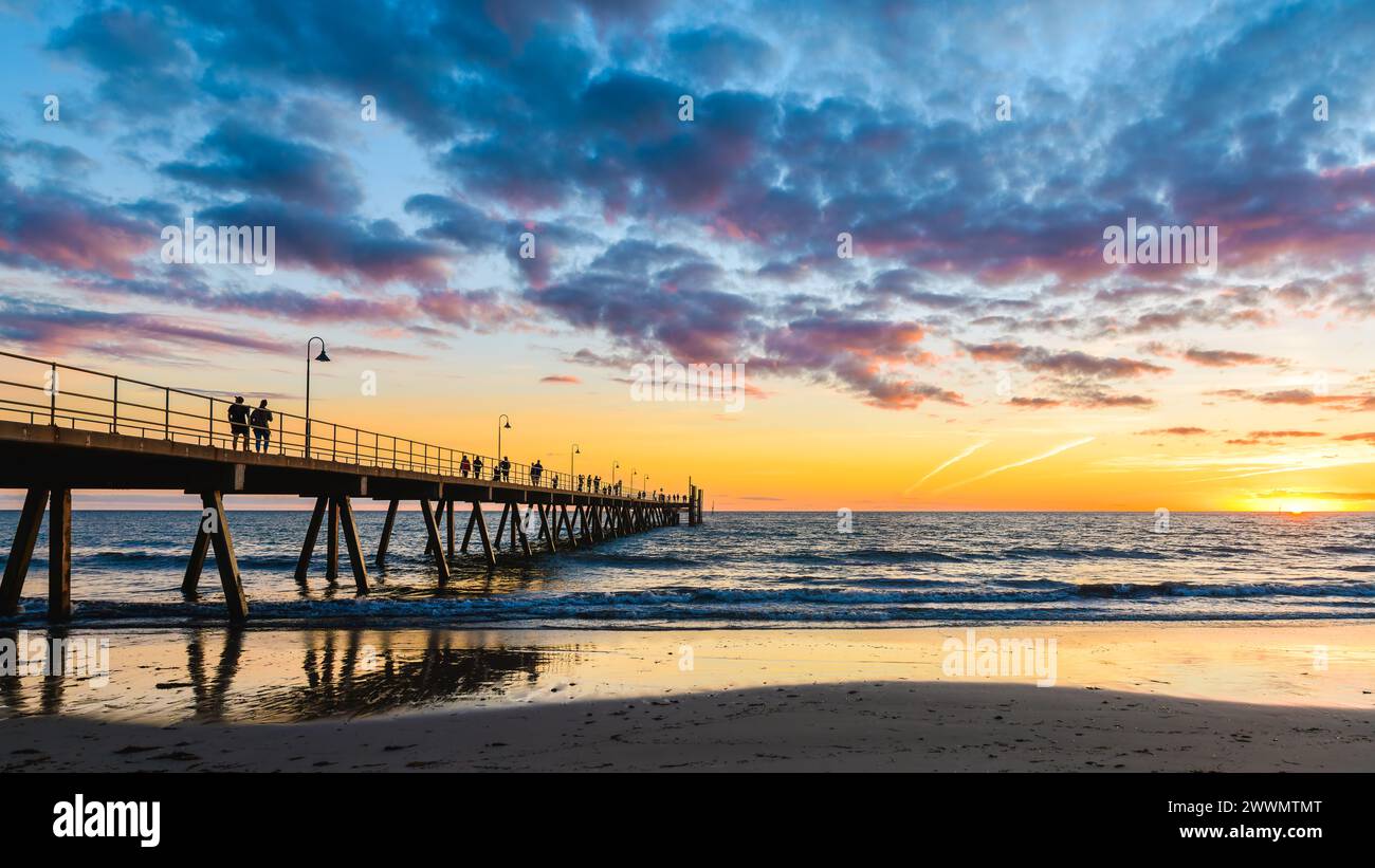 Glenelg Beach Pier mit Silhouetten für Spaziergänger bei Sonnenuntergang bei Sonnenuntergang, South Australia Stockfoto