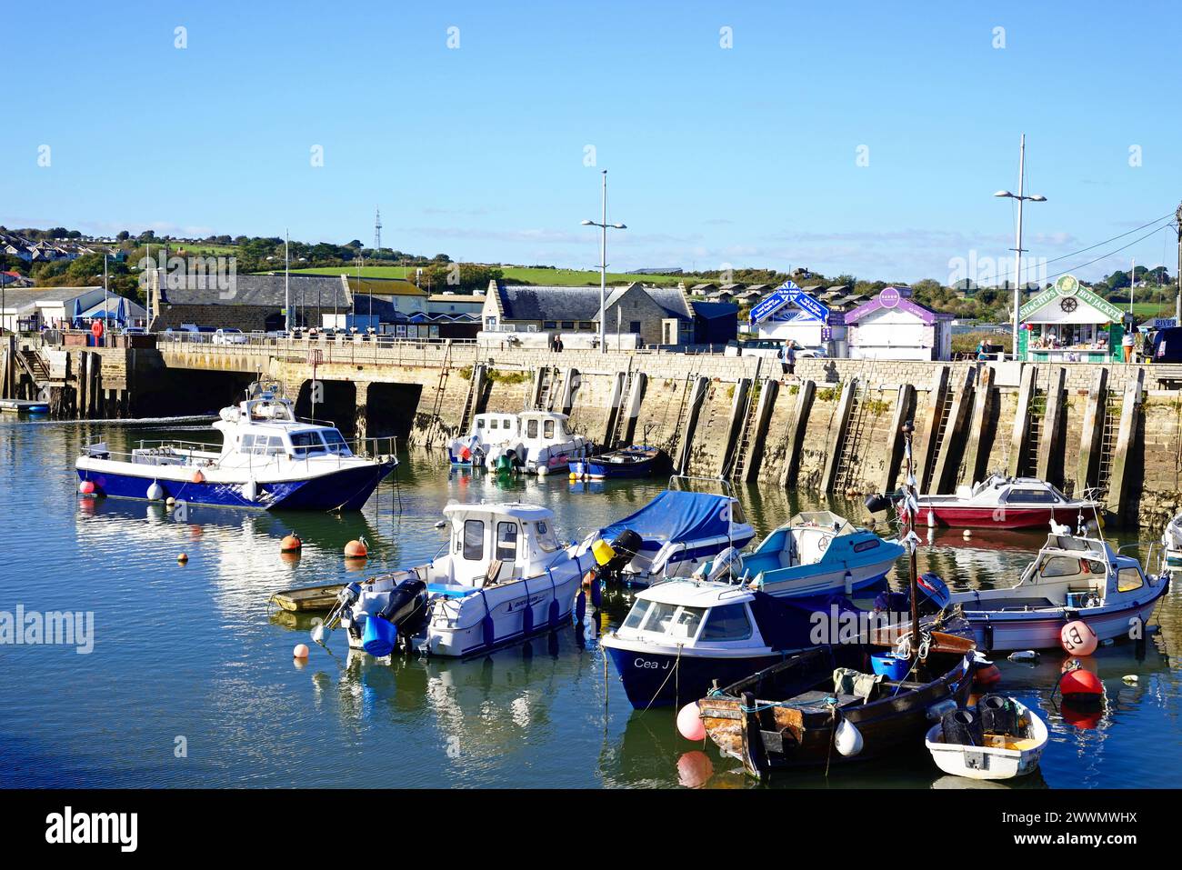 Blick auf traditionelle Fischerboote, die bei Ebbe im Hafen vertäut sind, mit der Stadt und der Landschaft nach hinten, West Bay, Dorset, Großbritannien, Europa. Stockfoto