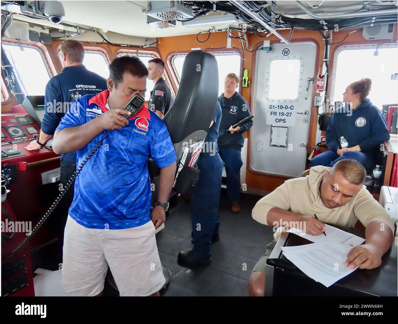 Die Besatzung der USCGC Oliver Henry (WPC 1140) und Schiffseigner der Kiribati Police Maritime Unit (PMU) führen Beobachtungsberichte über unter ausländischer Flagge fahrende Fischereifahrzeuge auf schwerer See während einer zentralen Etappe ihrer derzeitigen Expeditionspatrouille in der ausschließlichen Wirtschaftszone Kiribatis (AWZ) am 14. Februar 2024 durch. Zum ersten Mal seit 2015 nahm die Patrouille Schiffseigner der PMU ein und führte das 2008 mit Kiribati unterzeichnete bilaterale Seeverkehrsabkommen durch. Diese Engagements im Rahmen der Operation Blue Pacific unterstreichen das Engagement der Vereinigten Staaten, die Beziehungen zu stärken und die Sicherheit im Seeverkehr innerhalb der zu gewährleisten Stockfoto