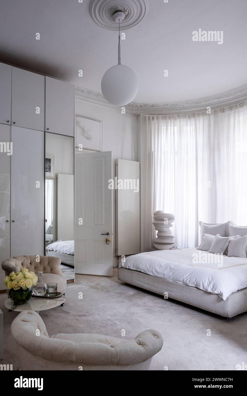Großer Spiegel in weißem Schlafzimmer mit moderner Kunstskulptur in West London Apartment, Großbritannien Stockfoto