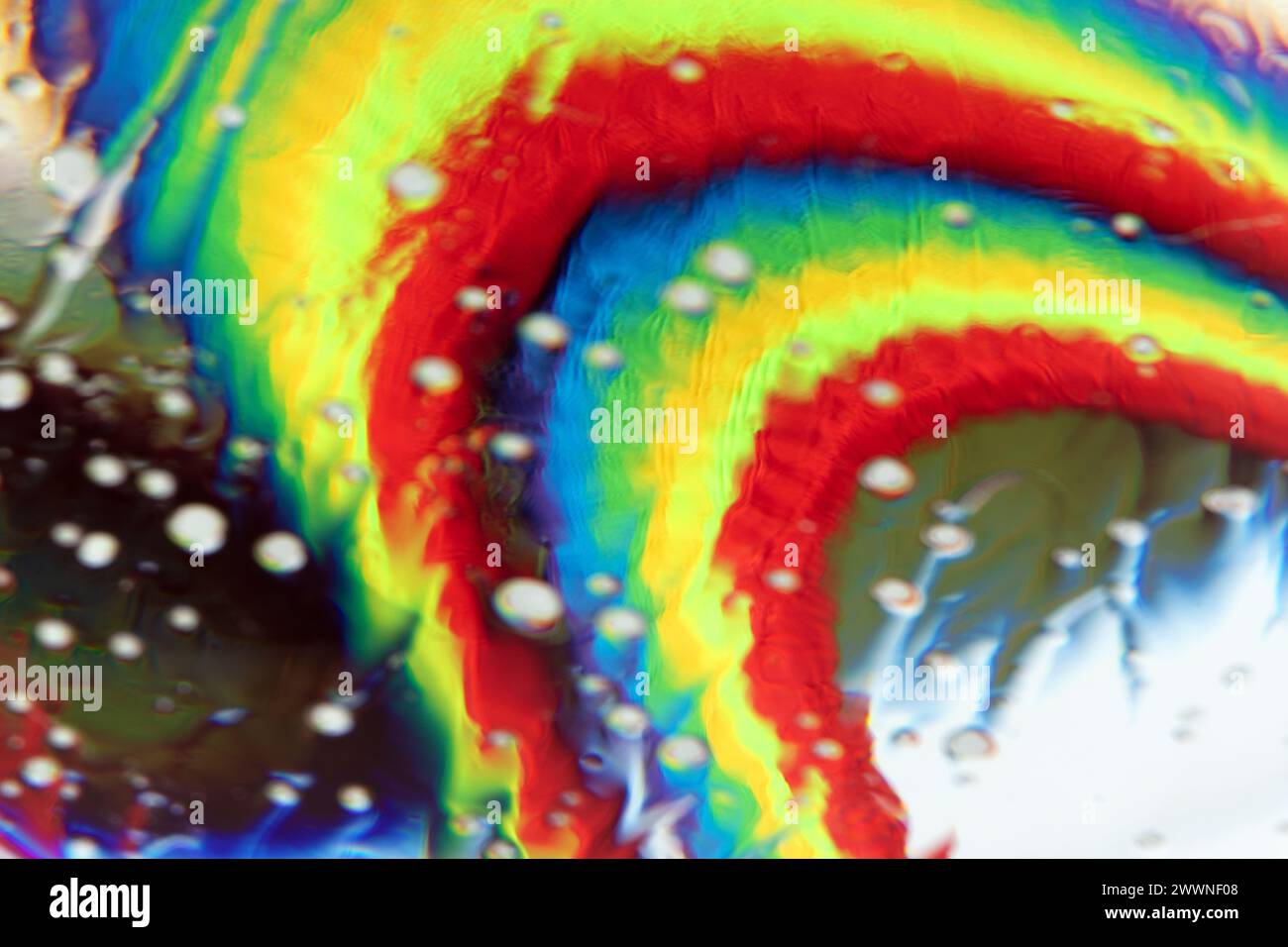 Optisch abstrakter Hintergrund von Regenbogengewebe mit Knicken und Lichteffekten in Wassertropfen. Stockfoto