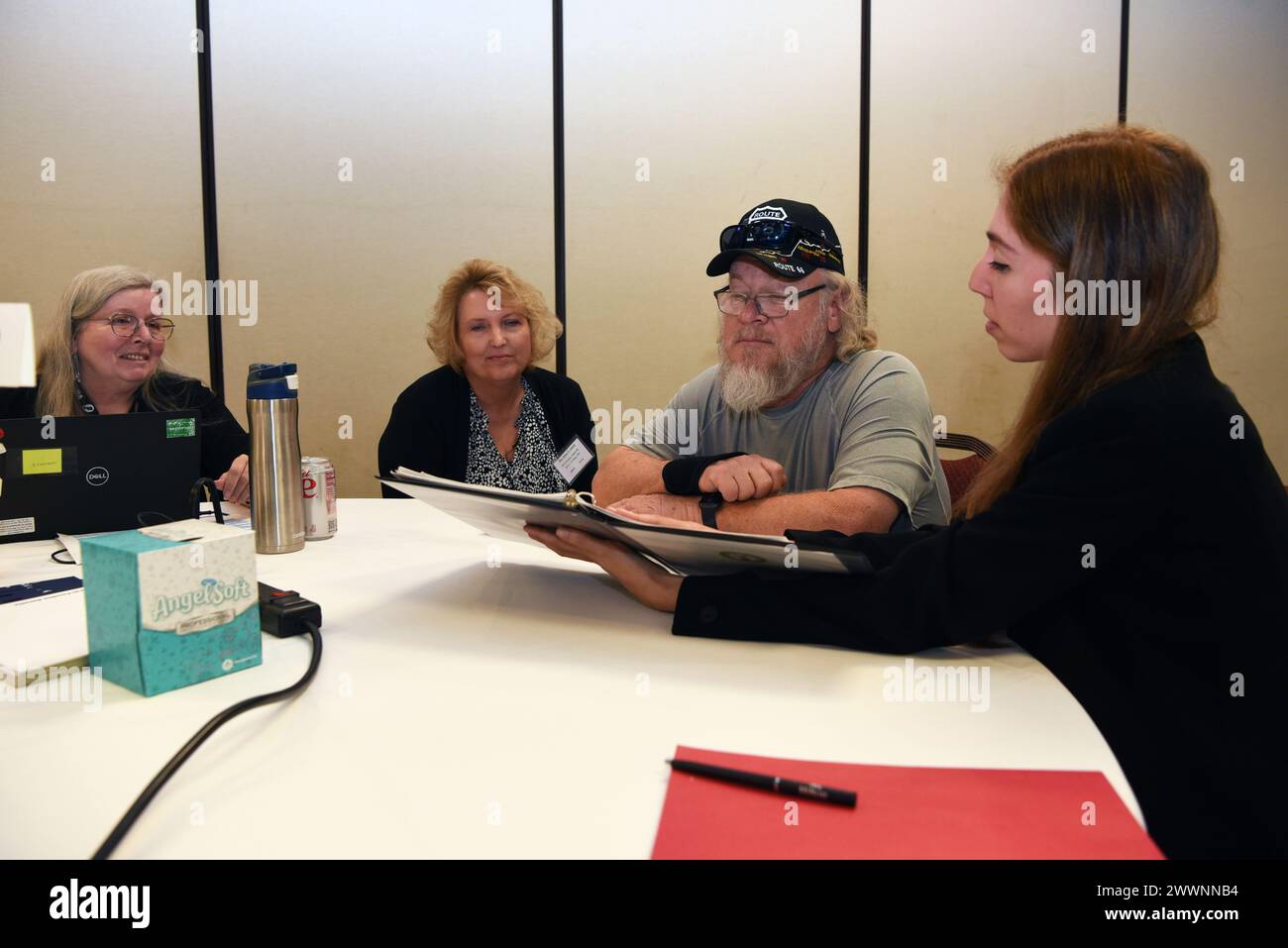 Cindy Holland, die US Army Casualty Office Service, unterhält mit Jenny Jansch und Robert Jansch über Jennys zweiten Cousin, US Army Private James Evans, als Claire Barnewalt, Analystin der Defense POW/MIA Accounting Agency (DPAA), ihnen während eines DPAA Family Member Update (FMU) in Phoenix, Ariz, verschiedene Aufzeichnungen von Evans zeigt. Februar 2024. FMU bieten Familienmitgliedern vermisster Amerikaner die Möglichkeit, persönlich mit Regierungsbeamten über ihren spezifischen Fall zu sprechen. Luftwaffe Stockfoto