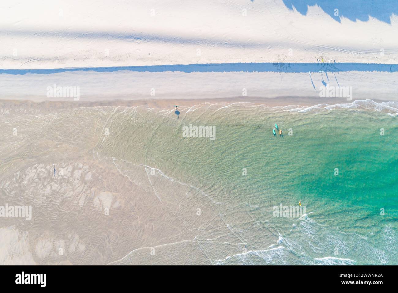 Surfer mit Boards am Strand. Türkisfarbenes Wasser und sauberer Strand im Sommer. Draufsicht von einer Drohne. Ein Blick aus der Vogelperspektive auf die Meereslandschaft. Recreati Stockfoto