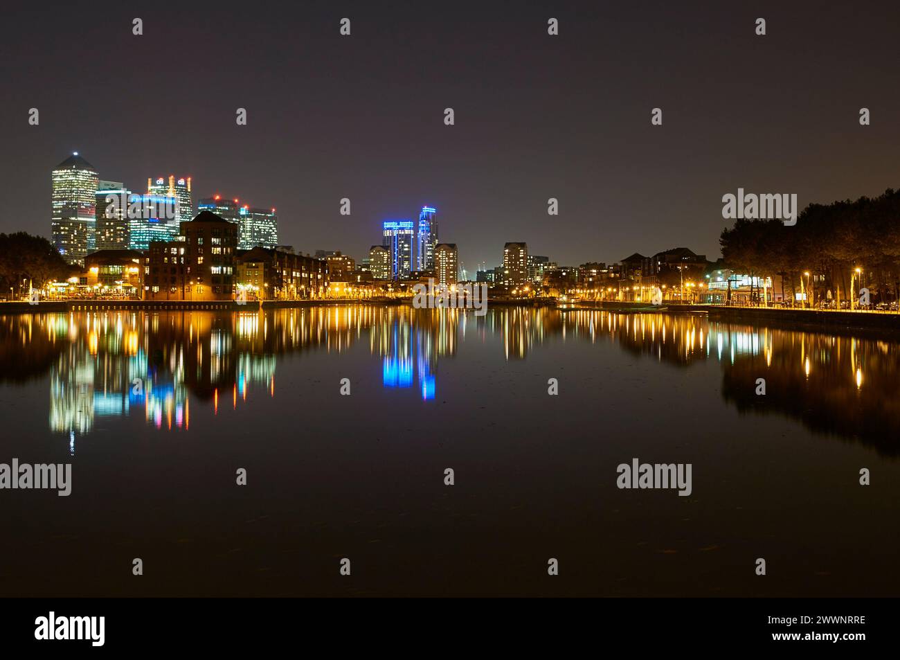 Greenland Dock, London Docklands UK, bei Nacht, Blick auf Canary Wharf, mit Reflexionen und beleuchteten Gebäuden Stockfoto
