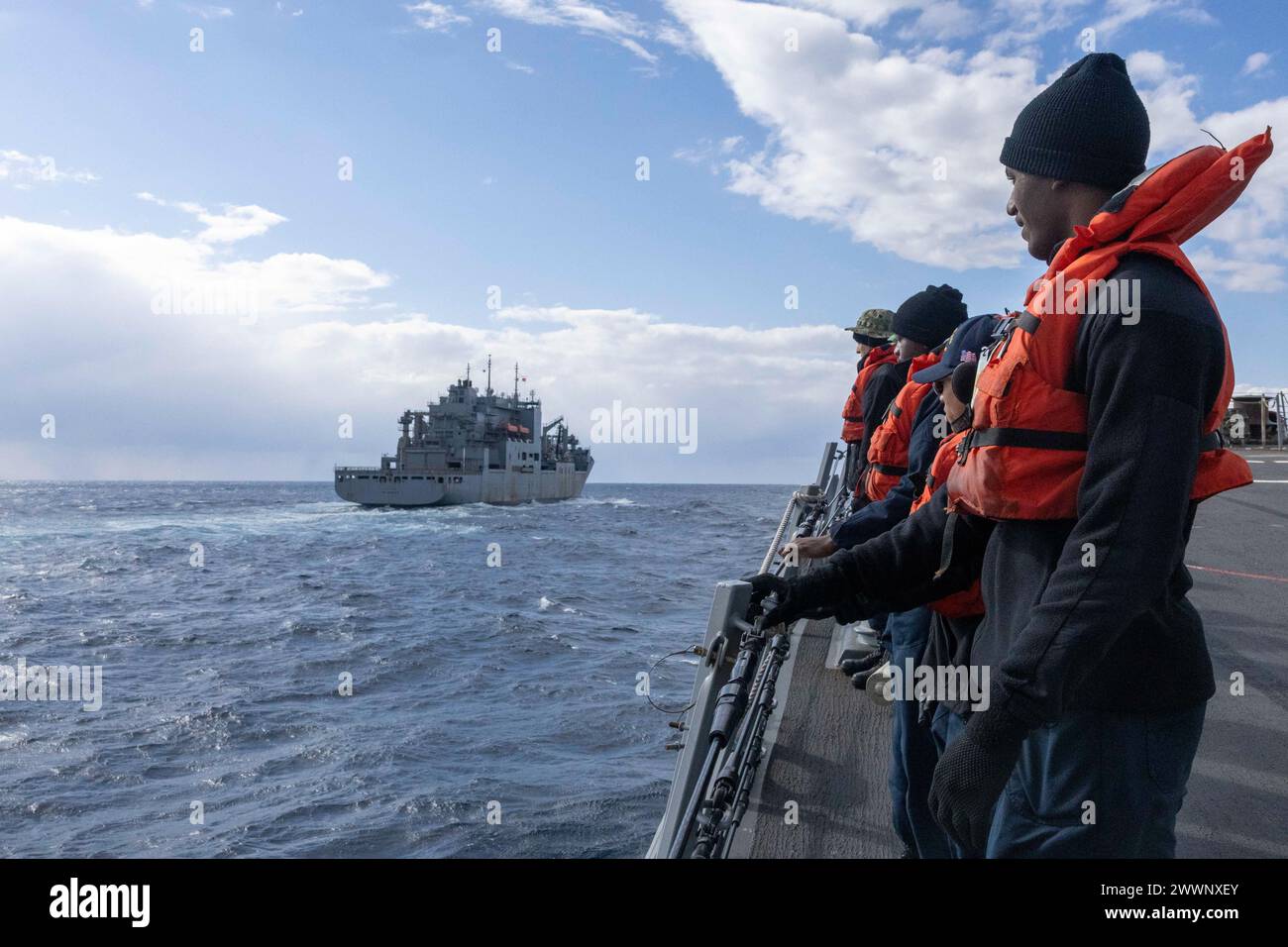 PHILIPPINE SEA (11. Februar 2024) Seeleute stehen bereit an Bord des Raketenzerstörers der Arleigh-Burke-Klasse USS Rafael Peralta (DDG 115), um während einer Auffüllung auf See an der Seite des Trockenfrachtschiffs der Lewis- und Clark-Klasse USNS Carl Brashear (T-AKE 7) zu ziehen. Brashear ist dem Military Sealift Command Far East (MSC FE) zugeordnet, das in Abstimmung mit dem Kommandeur, Task Force 73, entsandte Marinekräfte sowie regionale Verbündete und Partner im Indopazifik betankt und versorgt. Rafael Peralta wird vorwärtseingesetzt und dem Kommandeur der Task Force 71/Destroyer Squadron (DESRON) 15 zugewiesen, der Marine Stockfoto