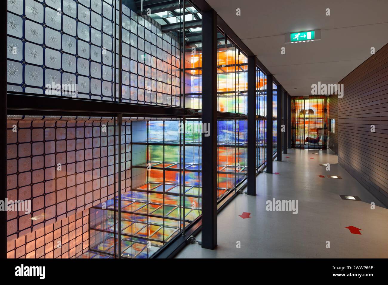 Korridor im Bürobereich, mit Atrium unten und Ziggurat dahinter, vor mehrfarbiger Glasfassade. Dutch Institute For Sound & Vision, Hilversum, Net Stockfoto