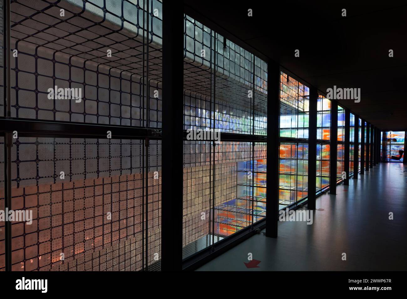 Korridor im Bürobereich, mit Atrium unten und Ziggurat dahinter, vor mehrfarbiger Glasfassade. Dutch Institute For Sound & Vision, Hilversum, Net Stockfoto