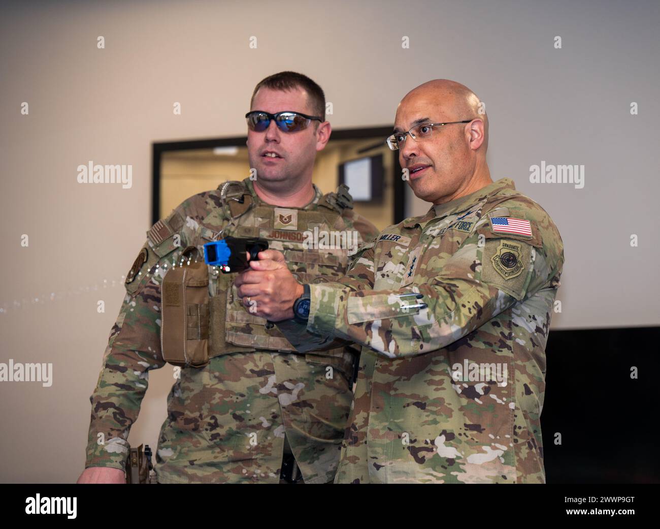 U.S. Air Force Tech. Sgt. Andrew Johnson, Trainer der 21. Sicherheitskräfte, links, unterstützt Generalleutnant David N. Miller Jr. beim Abfeuern eines Tasers auf der Peterson Space Force Base, Colorado, am 29. Februar 2024. Miller feuerte einen Taser auf ein stationäres Ziel im Rahmen seiner Space Base Delta 1-Tauchtour. Raumkraft Stockfoto