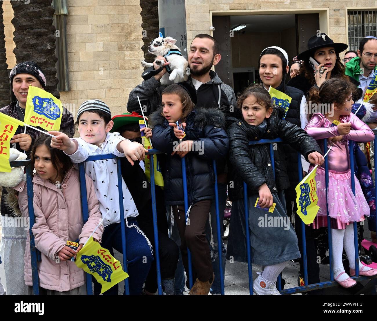 Jerusalem, Israel. März 2024. Ein Mann hält einen Hund auf der Schulter, während er die erste Purim-Parade in Jerusalem seit 1982, 42 Jahren am Montag, den 25. März 2024, beobachtet. Zehntausende Israelis kamen heraus, um die Parade während des andauernden Israel-Hamas-Krieges zu beobachten, während die Hamas noch 134 Geiseln in Gaza festhält. Purim feiert die Befreiung der Juden von einer Verschwörung, sie im alten Persischen vor 2,5000 Jahren zu vernichten. Foto: Debbie Hill/ Credit: UPI/Alamy Live News Stockfoto