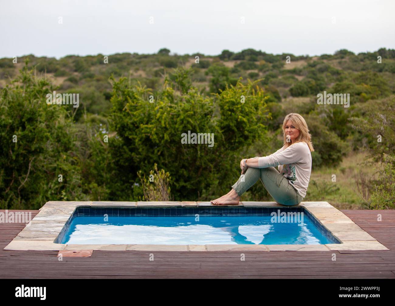 Frau genießt die Aussicht von einem Swimmingpool über den afrikanischen Busch im Amakhala Game Reserve in Südafrika, während sie sich auf einem luxuriösen 5-Sterne-Urlaub befindet. Stockfoto