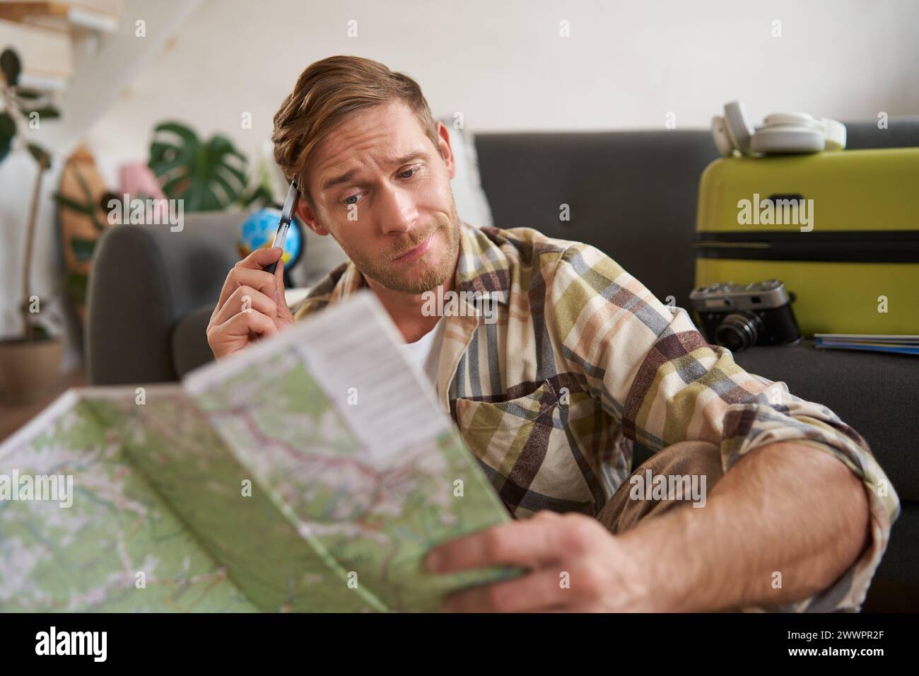 Porträt des Menschen, Touristen, die auf der Reisekarte verwirrt aussehen, zuckend, kann nicht entscheiden, welche Route Sie fahren möchten, wählen Sie die Straße für die Reise Stockfoto