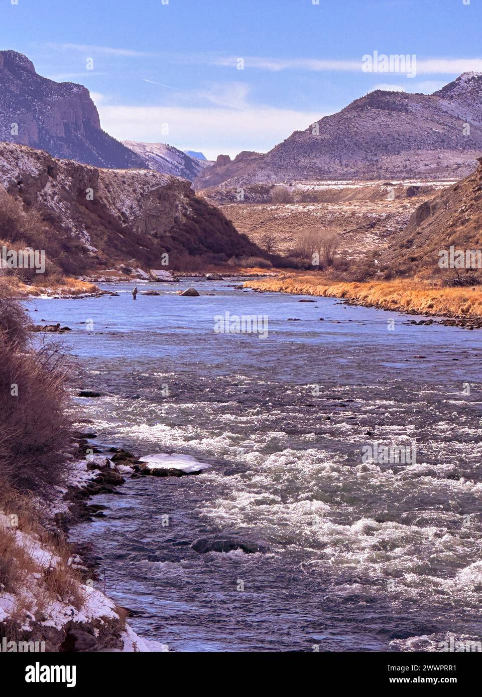 Fisherman stromaufwärts im schnell fließenden Shoshone River hat im Februar Winter einen Blick auf die Berge, die in den Yellowstone-Nationalpark von Cody, Wyoming, führen. Stockfoto