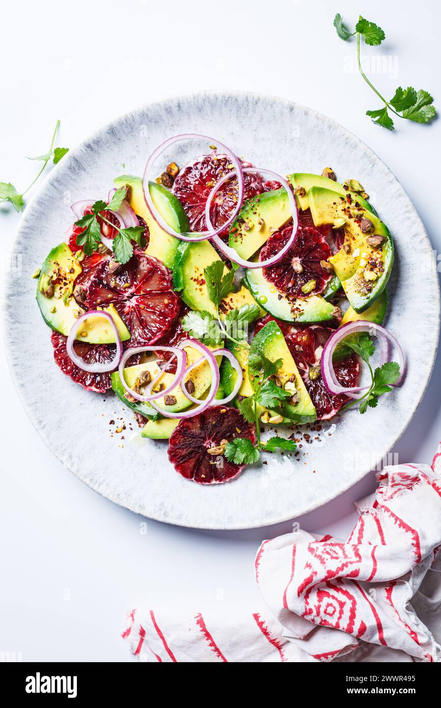 Blutorangen-Salat mit Avocado, Pistazien und roten Zwiebeln, Blick von oben, weißer Hintergrund. Stockfoto