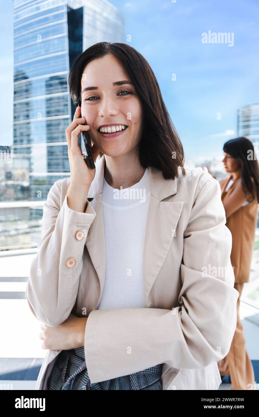 Eine Frau redet auf ihrem Handy. Sie lächelt und ist gut gelaunt Stockfoto