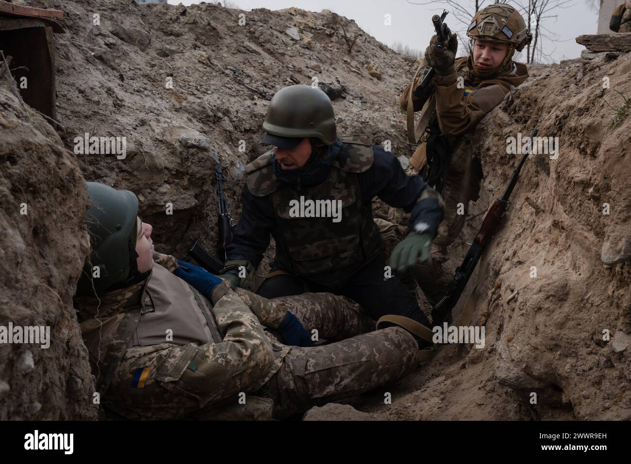 15. März 2024, Kiew, Ukraine: Auszubildende nähern sich einem potenziell verletzten Soldaten in einer Ausbildung, die eine Evakuierungsmission im Graben simuliert, die von der dritten separaten Sturmbrigade in Kiew organisiert wird. Die Ukraine ist mit einem Mangel an Munition und militärischem Personal konfrontiert. Abgesehen von einem verschärften Mobilisierungsgesetz haben sich einige Brigaden im Land für einen ermutigenderen Ansatz entschieden, Menschen ohne vorherige militärische Erfahrung für den Einsatz in der Armee zu rekrutieren. Die dritte separate Sturmbrigade bietet einen 7-tägigen kostenlosen Trainingskurs an, um den Teilnehmern einen Vorgeschmack auf militärische Tragen zu geben Stockfoto