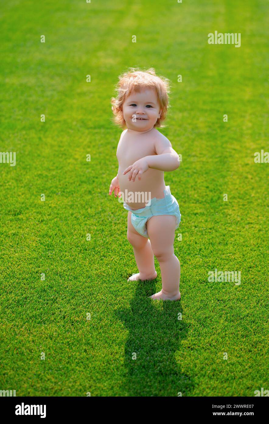 Nettes witziges lachendes Baby, das kriechen lernt und Spaß beim Spielen auf dem Rasen hat und den Sommer im Garten beobachtet. Glück und Harmonie im Familienleben. Stockfoto
