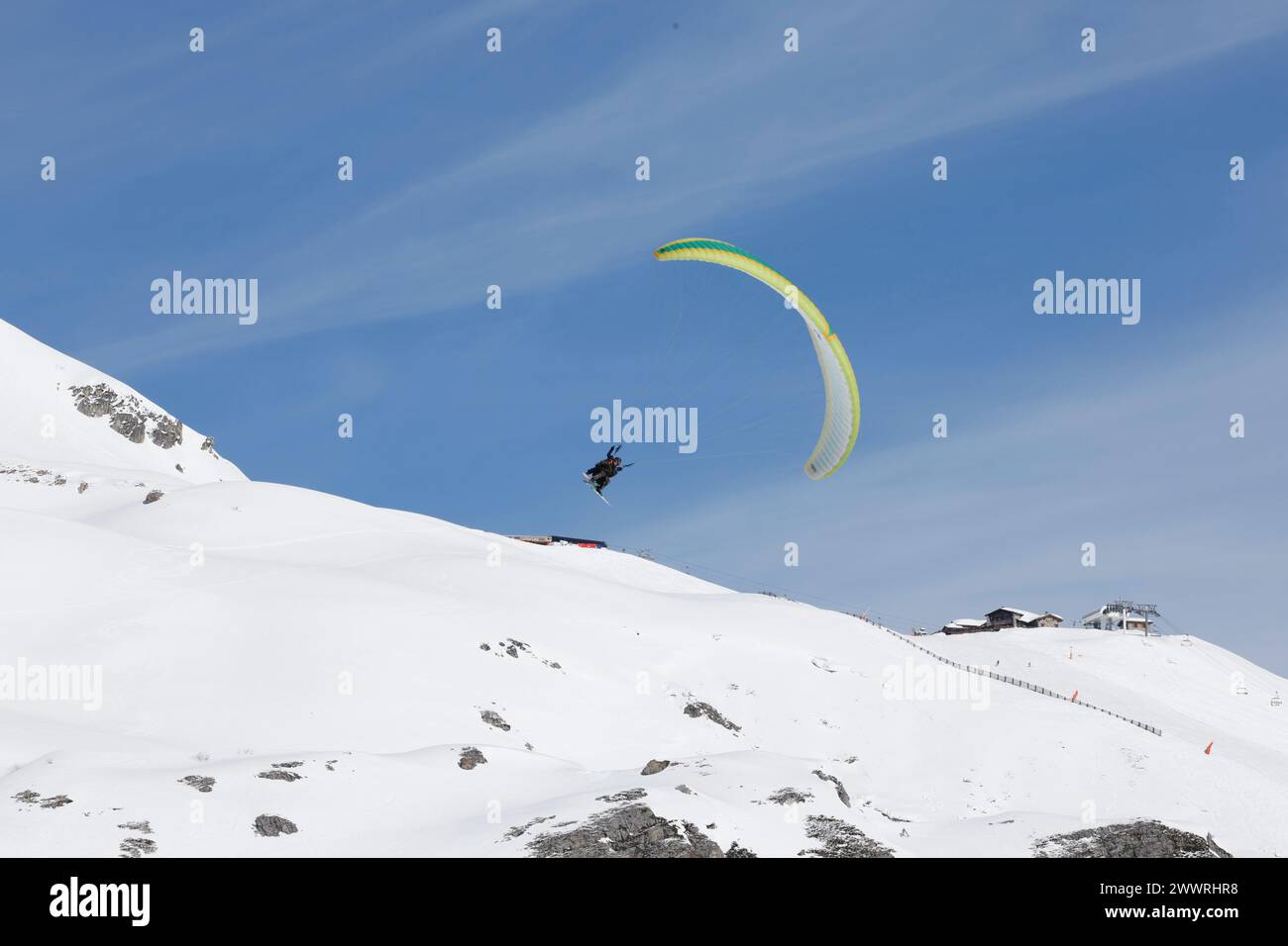 Ein Gleitschirmflieger auf Tandemflugplätzen über Schnee und Felsen in Tignes, einem hochgelegenen Skigebiet in den französischen Alpen. Stockfoto