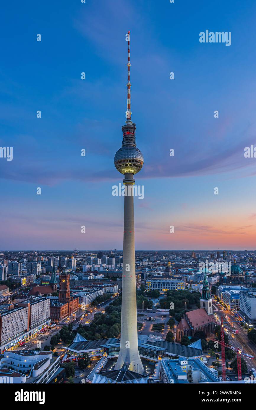 Fernsehturm im Zentrum Berlins. Sonnenuntergang mit wenigen Wolken. Beleuchtete Straße und Gebäude am Alexanderplatz. Wahrzeichen der Hauptstadt Stockfoto
