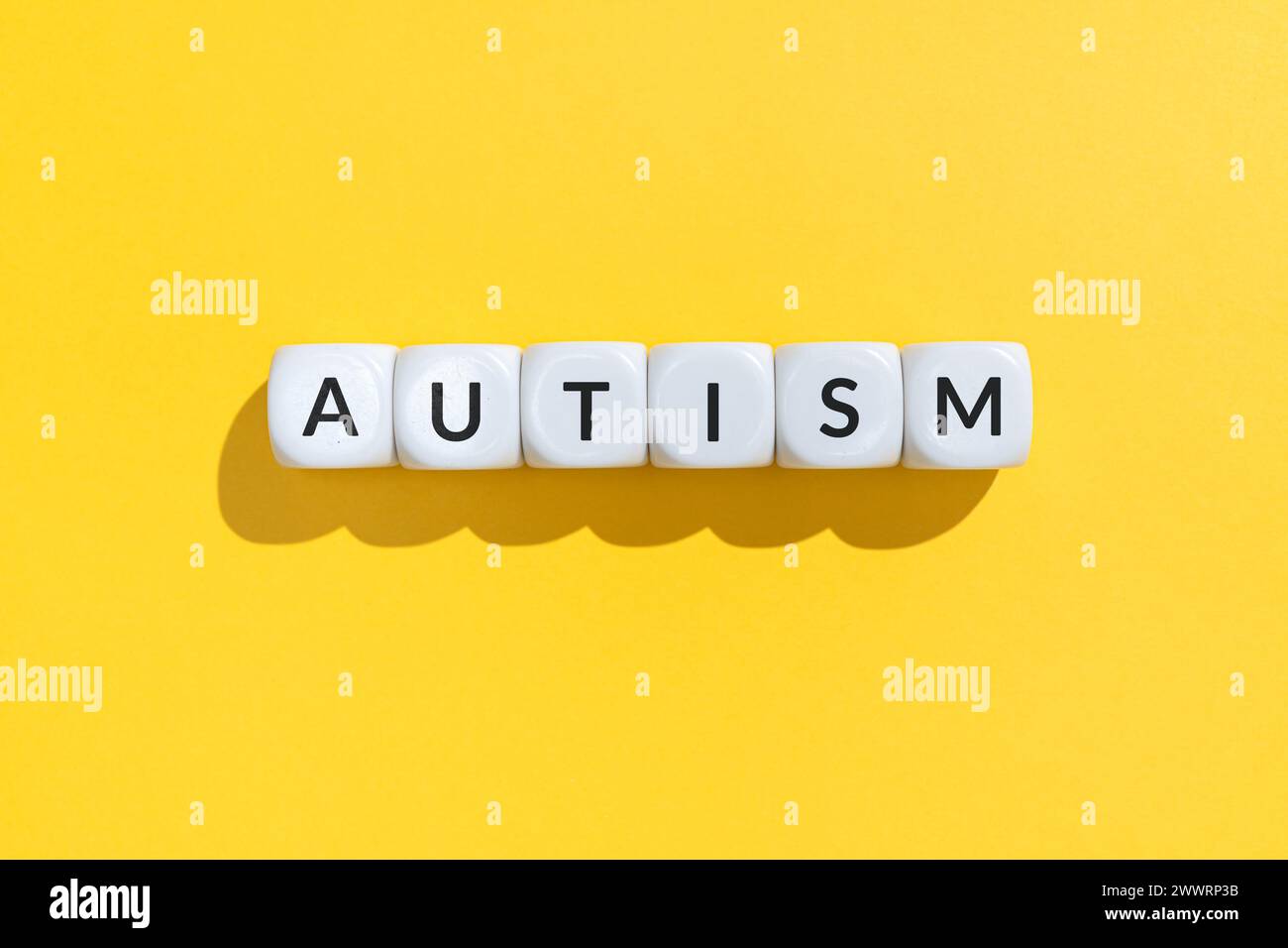 Autismuswort auf weißen Würfelblöcken isoliert auf gelbem Hintergrund Stockfoto