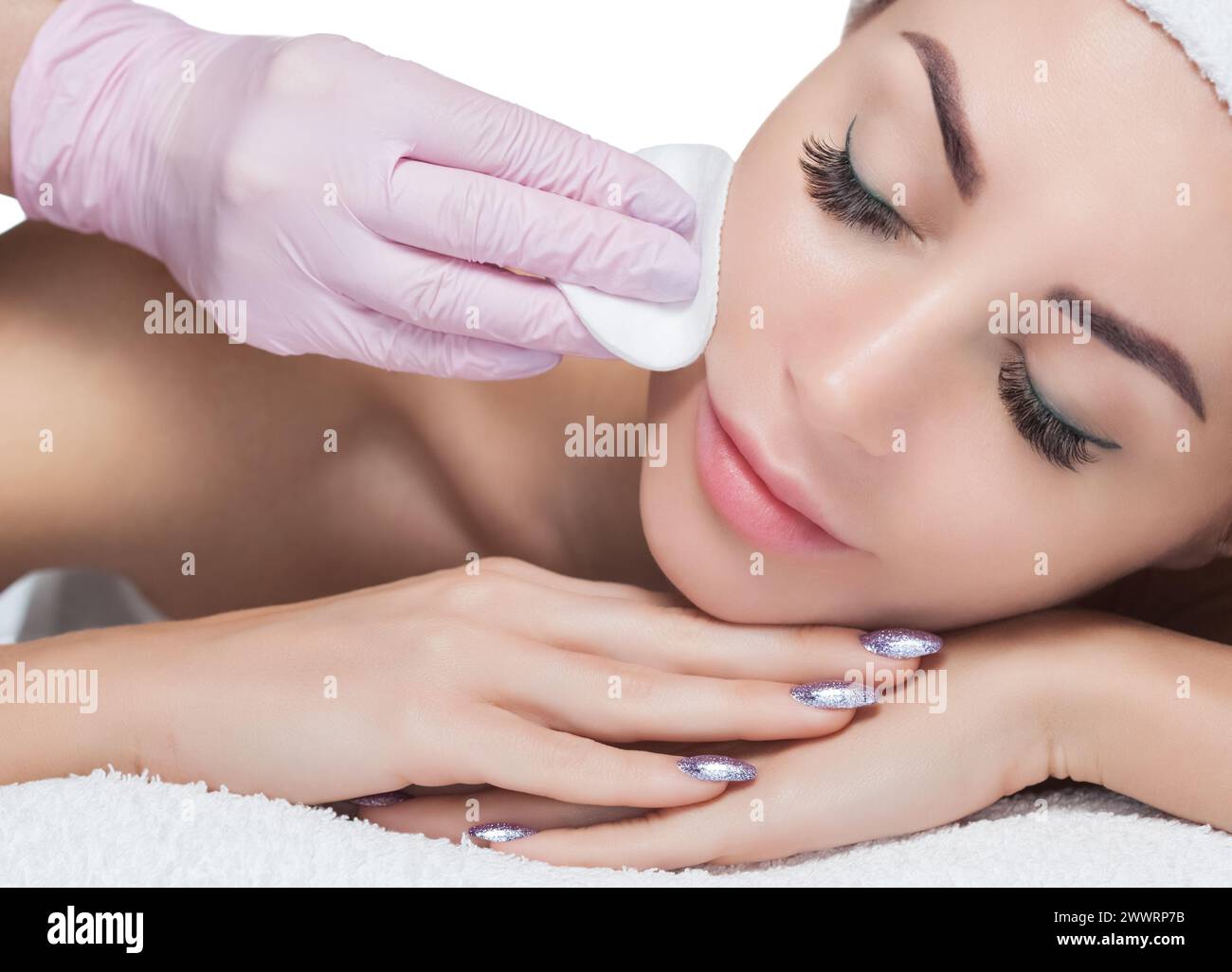 Der Arzt Kosmetikerin reinigt mit einem Tonikum die Gesichtshaut einer schönen, jungen Frau in einem Schönheitssalon.Kosmetik Hautpflege. Stockfoto