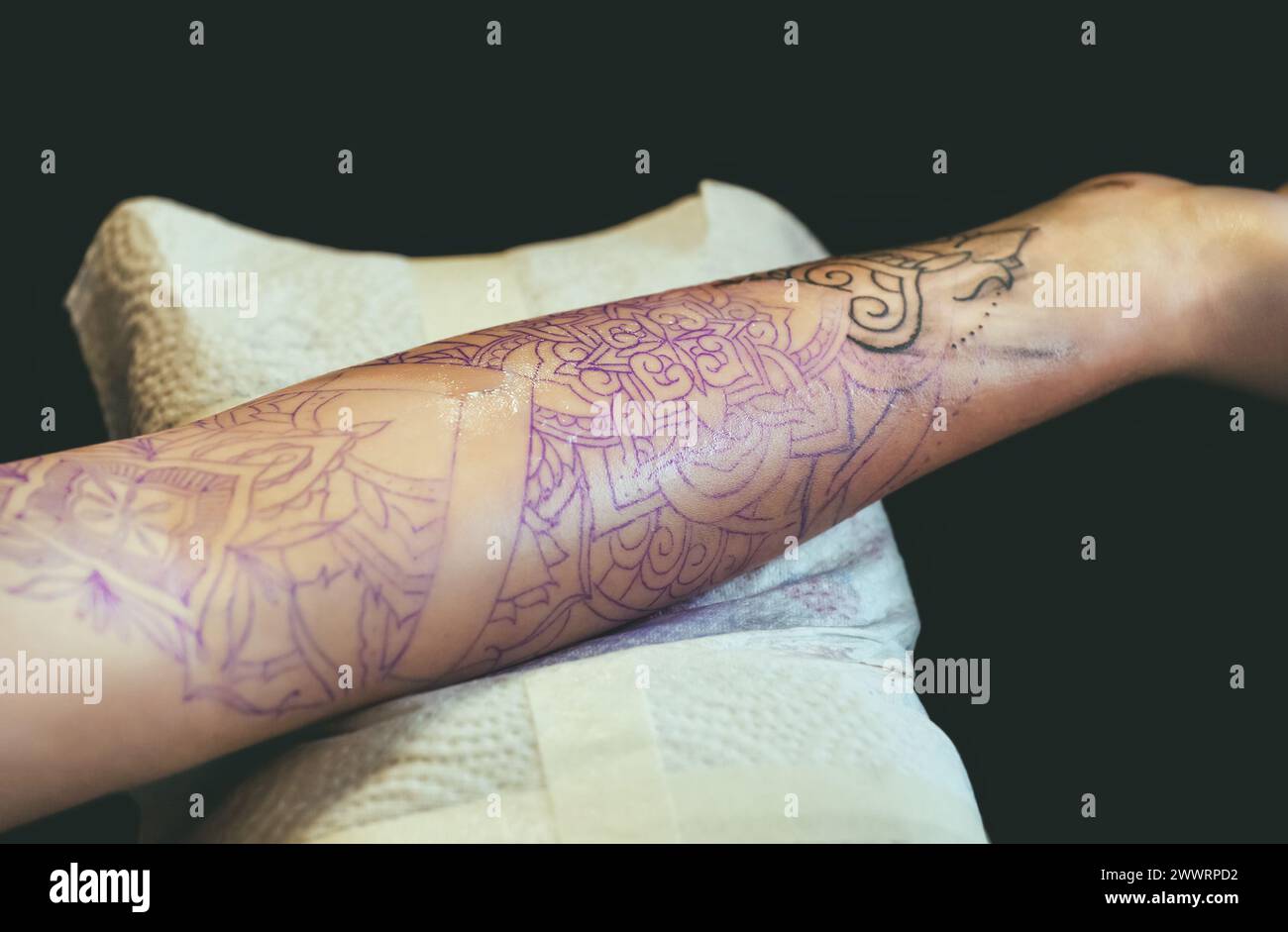 Tattoo Master Schutzhandschuhe machen ein Tattoo in schwarzer Tinte auf der Hand des Mädchens. Stockfoto