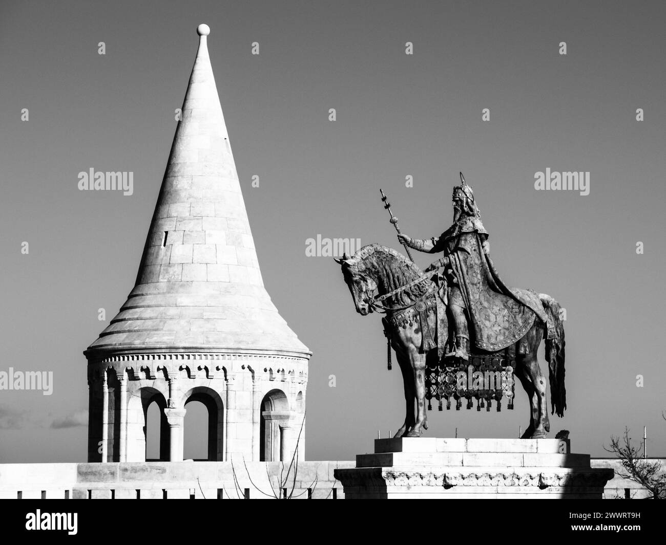 Auf dem Berg befindliche Statue des Heiligen Stephan I., alias Szent Istvan kiraly - der erste König von Ungarn an einem typischen weißen Rundturm der Fischerbastei in der Budaer Burg in Budapest, Ungarn, Europa. Sonnenaufnahme mit blauem Himmel im Hintergrund. Schwarzweißbild. Stockfoto