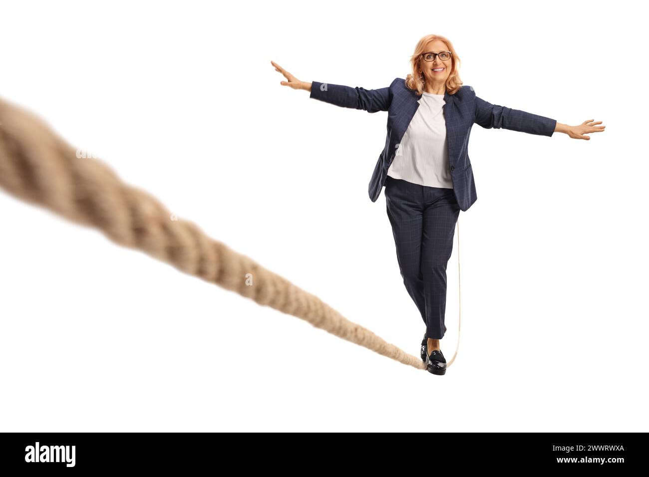 Porträt einer Frau mittleren Alters, die auf einem Seil auf weißem Hintergrund läuft Stockfoto
