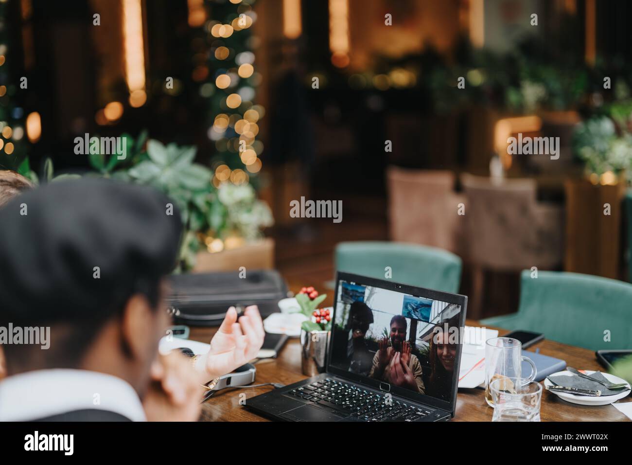 Multiethnische Experten arbeiten bei einem virtuellen Meeting in einem Restaurant zusammen und präsentieren Teamwork und moderne Arbeitsdynamik. Stockfoto