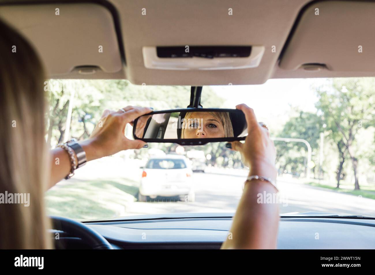 Fahrerin, die den Rückspiegel ihres Autos einstellt. Stockfoto