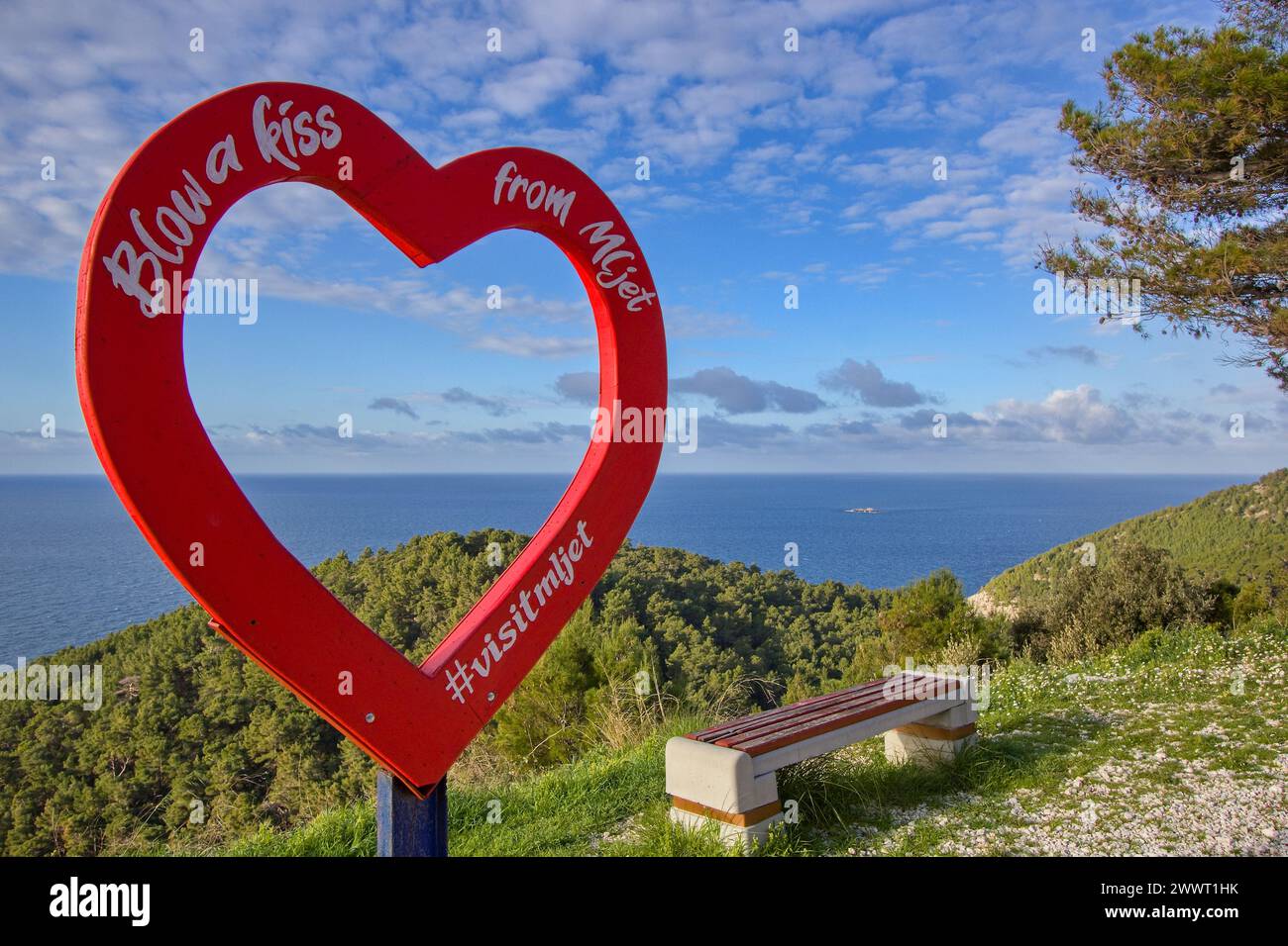 Bilderrahmen in roter Herzform: Blasen und Küssen von der Insel Mljet, Kroatien mit Blick auf die Adria und einer romantischen Bank. Stockfoto