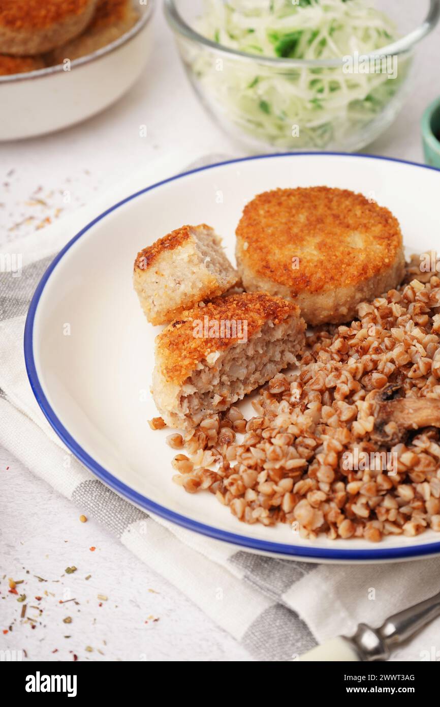 Teller mit leckeren Fleischschnitzeln mit Buchweizen auf weißem Hintergrund Stockfoto