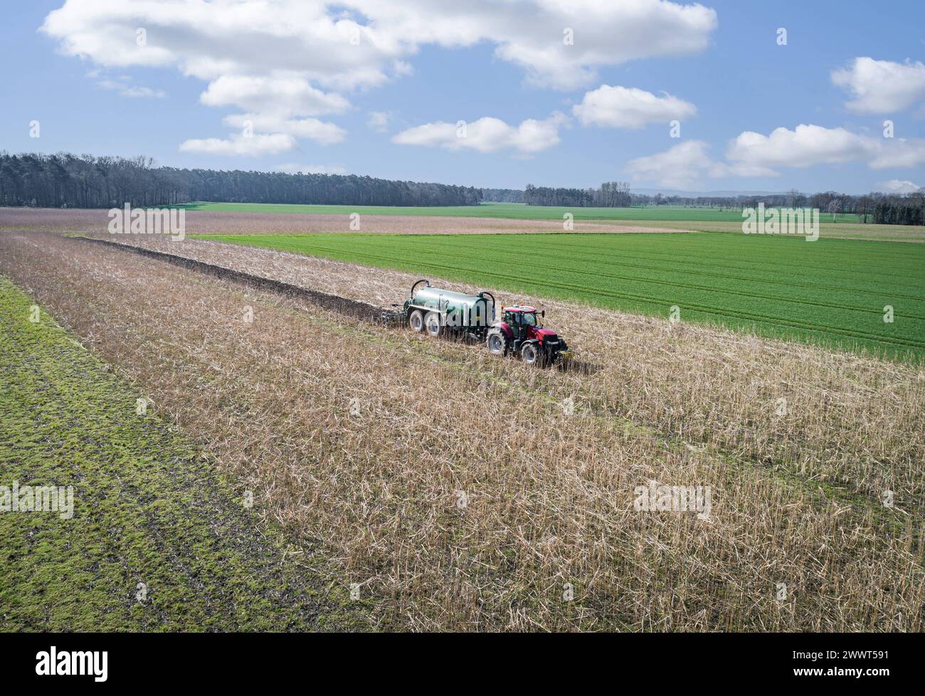 Gülleausbringung - bei modernen Güllefässern wird die Gülle in einem Arbeitsgang im Boden eingearbeitet, Luftaufnahme. Ab etwa Anfang April beginnen Landwirte damit, Wirtschaftsdünger in Form von Gülle oder auch Gärreste aus Biogasanlagen für die Maisaussaat aufs Feld zu bringen. Bei großen Entfernungen zu den Ackerflächen wird ein zusätzliches Tankfahrzeug für den Transport vom Hof eingesetzt. Moderne Ausbringungstechnik - z.B. Güllefässer mit Schleppschlauchverteilern oder eine am Güllefass nachlaufende Scheibenegge sorgen für umgehende Einarbeitung des Wirtschaftsdüngers im Boden. Raumschaft Stockfoto