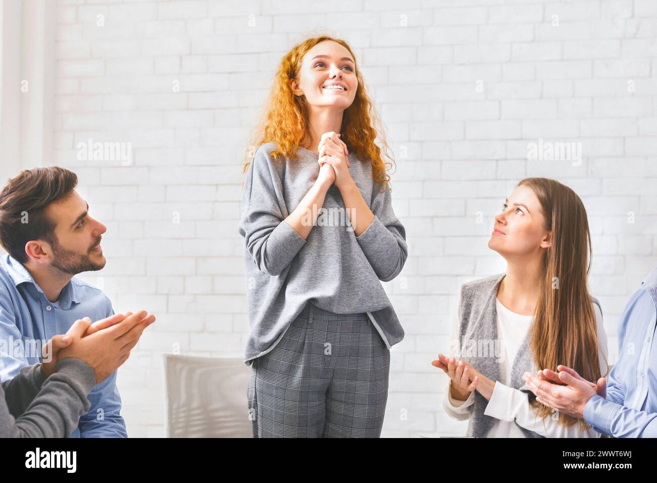 Fröhliche junge Frau, die während einer Psychotherapiesitzung vor der Gruppe spricht Stockfoto