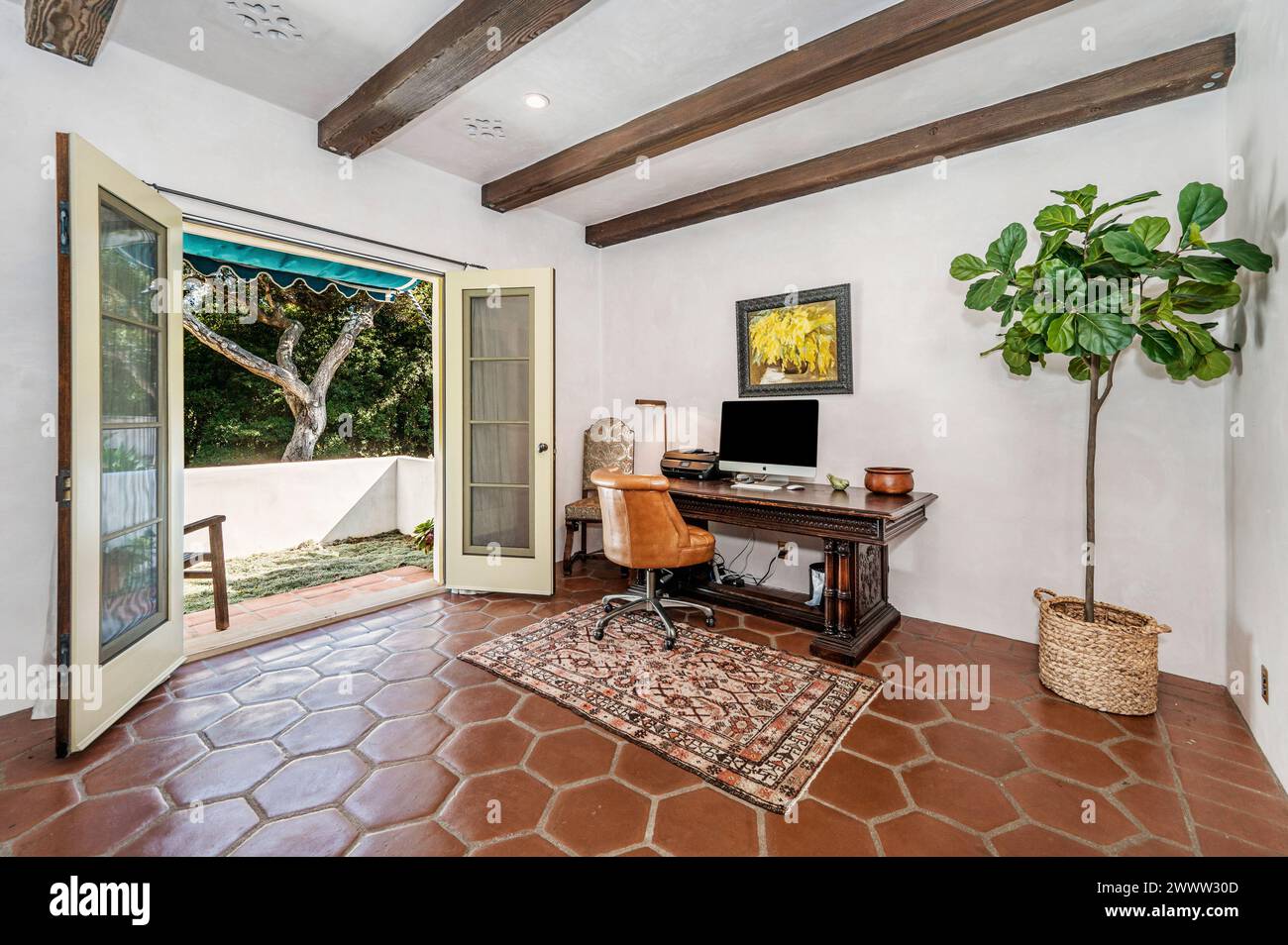 Ein Bürobereich mit großen Fenstern, Grün und einem eleganten Schreibtisch Stockfoto