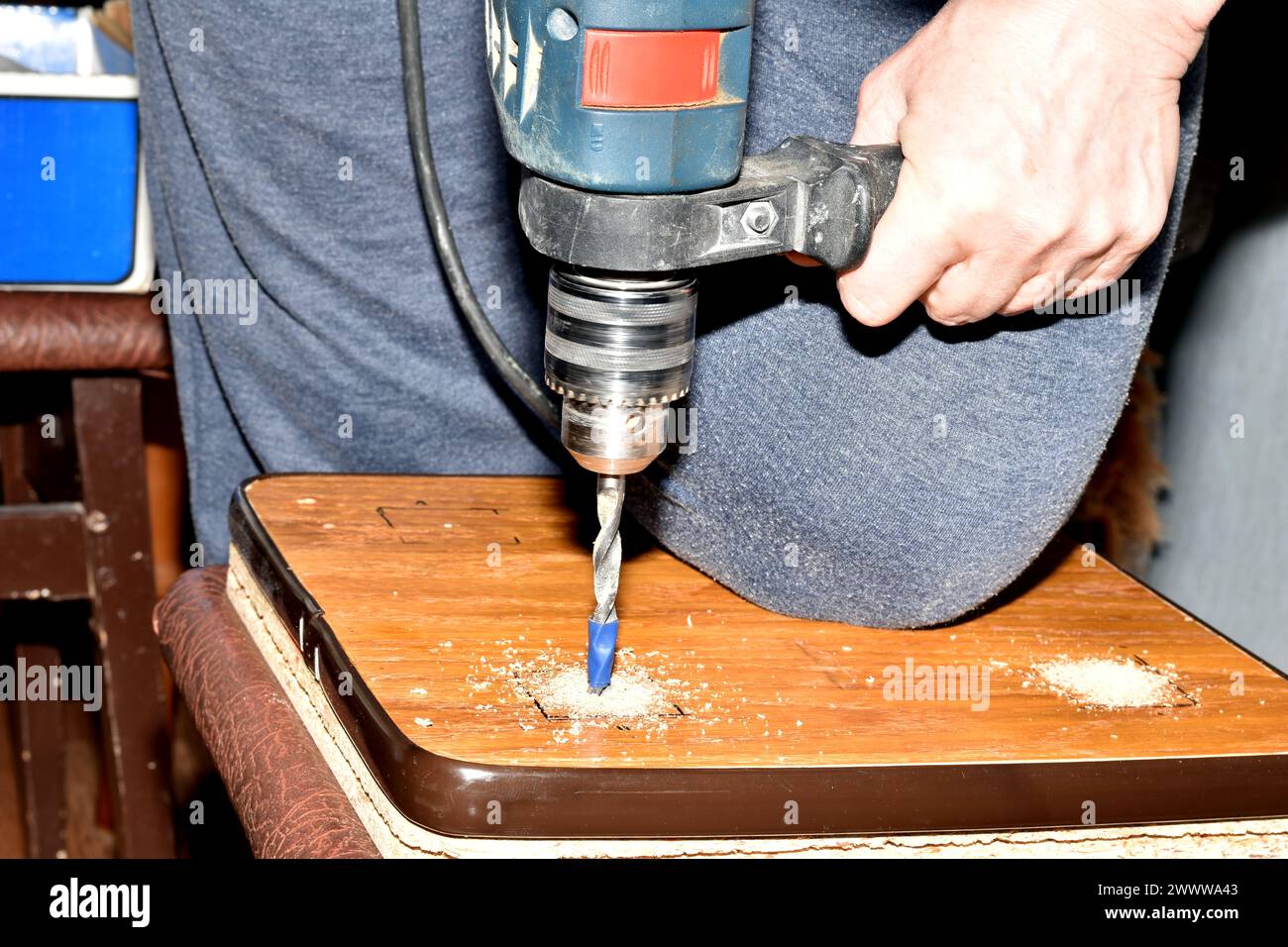Man bohrt Löcher auf Holzbretter für die Herstellung von handwerklichen Möbeln zu Hause. Montagemöbel. Hochwertige Fotos Stockfoto