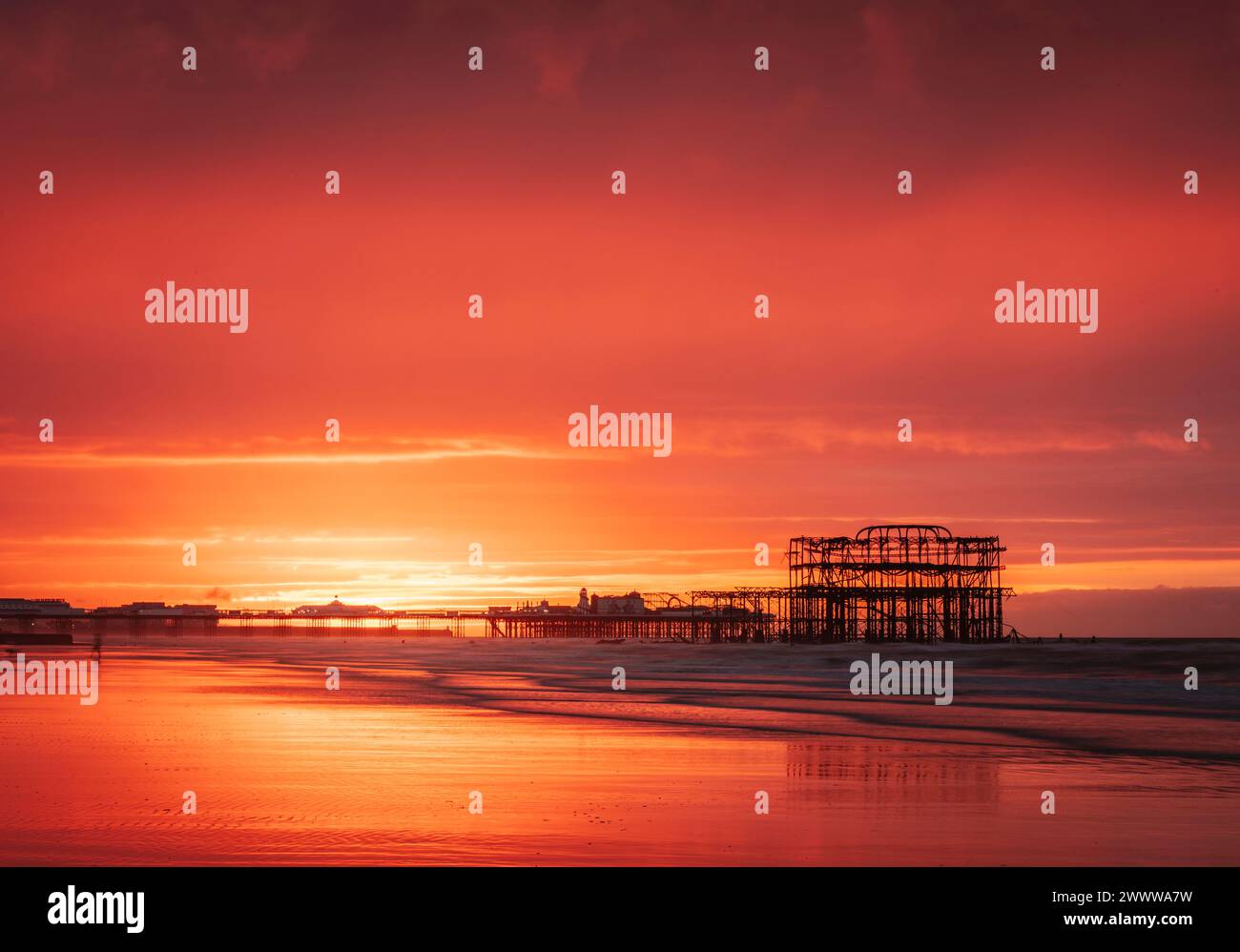 Brighton West Pier und Palace Pier während eines sehr lebhaften roten Sonnenaufgangs an der Ostküste von Sussex im Südosten Englands Großbritannien Stockfoto
